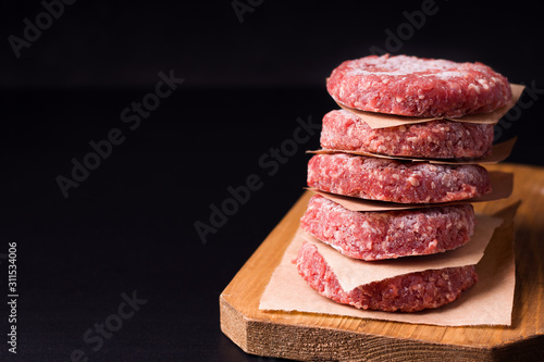 frozen raw minced meat in the form of cutlets on a black background. have copy space