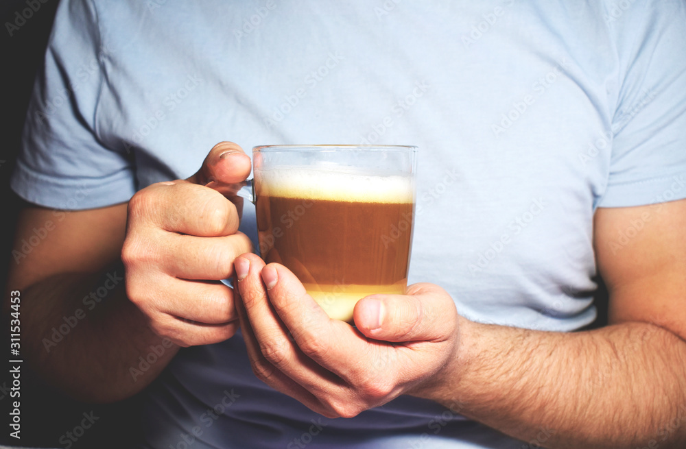 Close-up of a man's hands holding a Cup of latte coffee. The lifestyle of an adult businessman in weekend activities is relaxing. Concept of drinking coffee. Close-up of a man's hands holding a Cup of latte coffee. The lifestyle of an adult businessman in weekend activities is relaxing. Concept of drinking coffee.