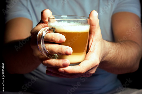Close-up of a man's hands holding a Cup of latte coffee. The lifestyle of an adult businessman in weekend activities is relaxing. Concept of drinking coffee.