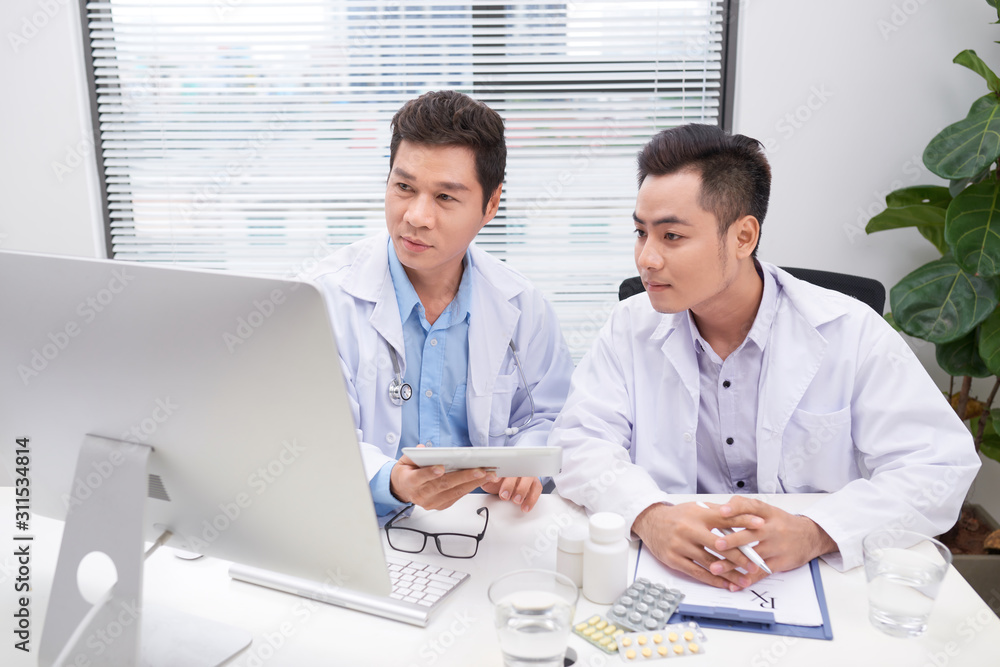 Two doctors holding and talking about patient on office Two doctors holding and talking about patient on office