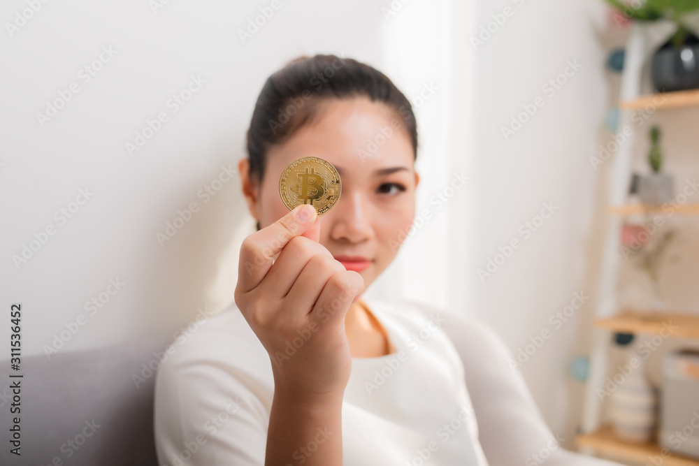 Asian woman gets big money! Attractive woman with holds bitcoin in hands and looks into the camera. Asian woman gets big money! Attractive woman with holds bitcoin in hands and looks into the camera.