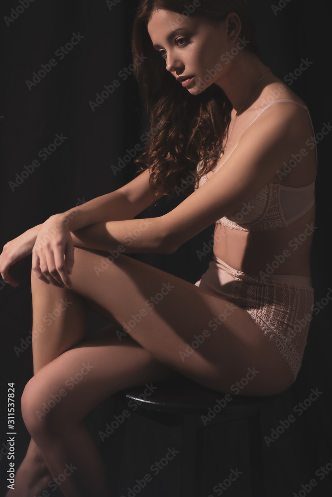 cropped view of sexy young woman in lingerie sitting on black background cropped view of sexy young woman in lingerie sitting on black background