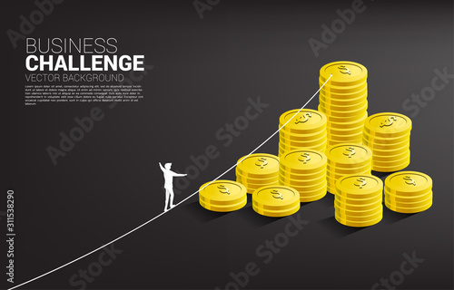 Silhouette of businessman walking on rope walk way to golden coin stack .Concept for business risk and career path