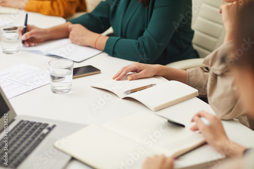 Horizontal high angle shot of urecognizable women sitting at office table working together in team