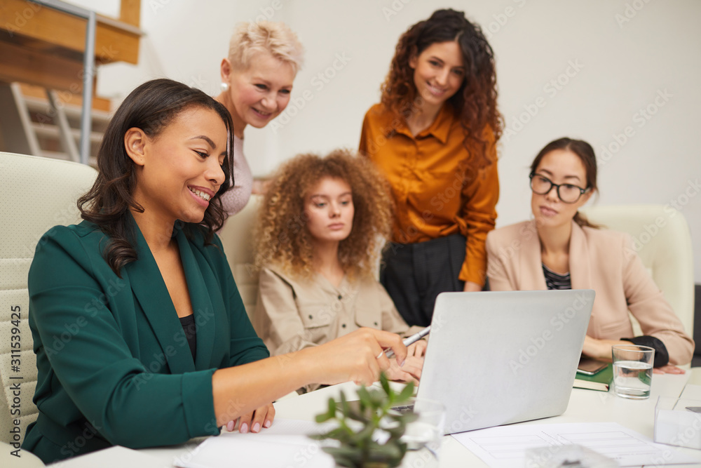 Group of five attractive female office workers watching something on laptop during business meeting Group of five attractive female office workers watching something on laptop during business meeting