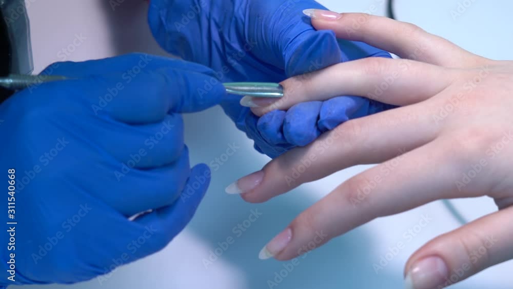 Closeup view of professional manicurist doing manicure to client at beauty spa salon. Worker uses nail pusher to cuticles of fingers. Real time 4k video footage. Closeup view of professional manicurist doing manicure to client at beauty spa salon. Worker uses nail pusher to cuticles of fingers. Real time 4k video footage.