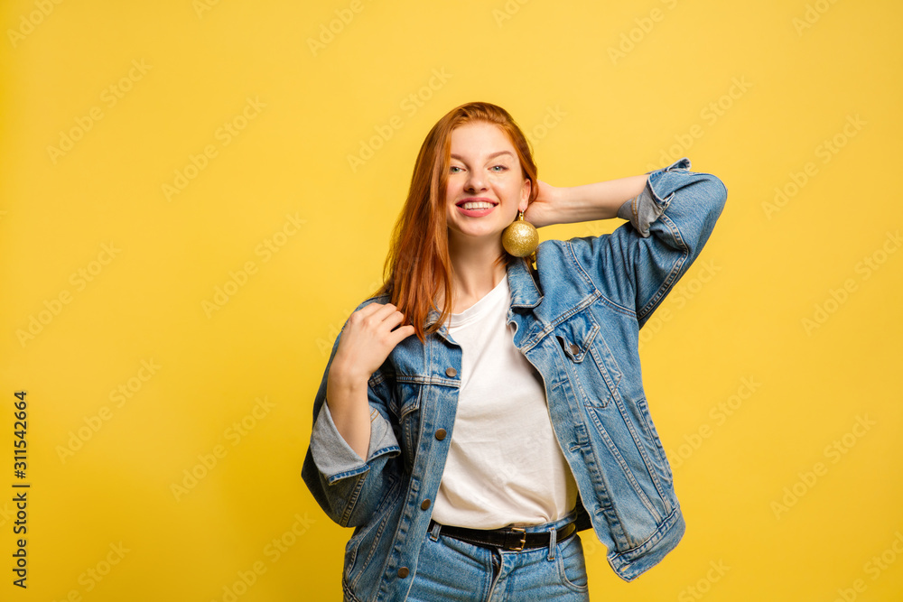 New Year's look. Caucasian woman's portrait on yellow studio background. Beautiful female red hair model in jeanse. Concept of human emotions, facial expression, sales, ad, winter mood, Christmas. New Year's look. Caucasian woman's portrait on yellow studio background. Beautiful female red hair model in jeanse. Concept of human emotions, facial expression, sales, ad, winter mood, Christmas.