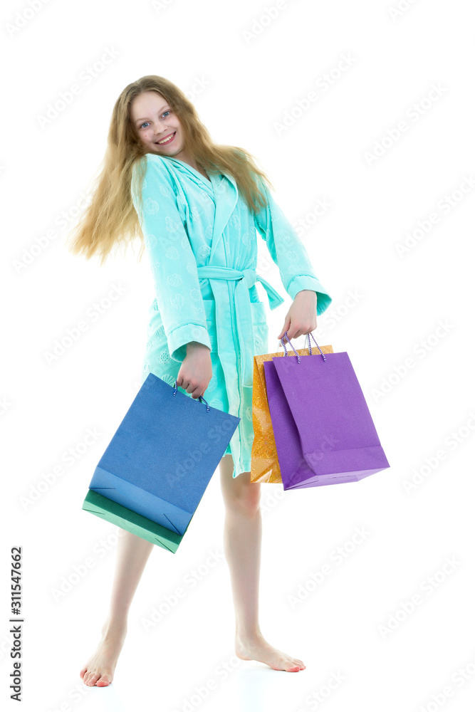 Cheerful girl in a short robe waving multicolored paper bags. Th