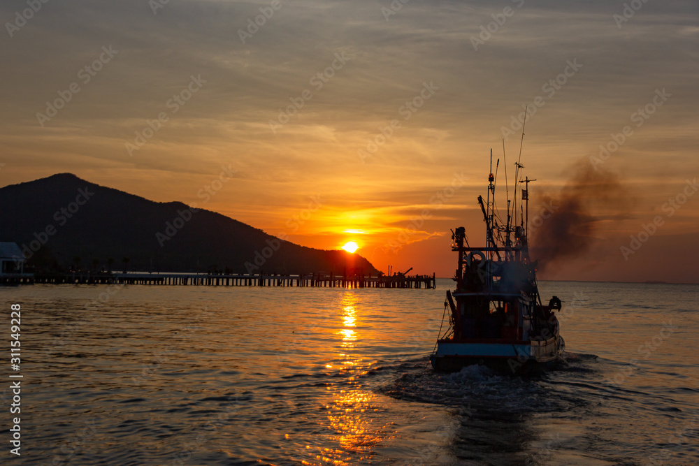 The fishermen drove the fishing boat to the sea on sunset and dramatic clound.Silhouette of fishing boat