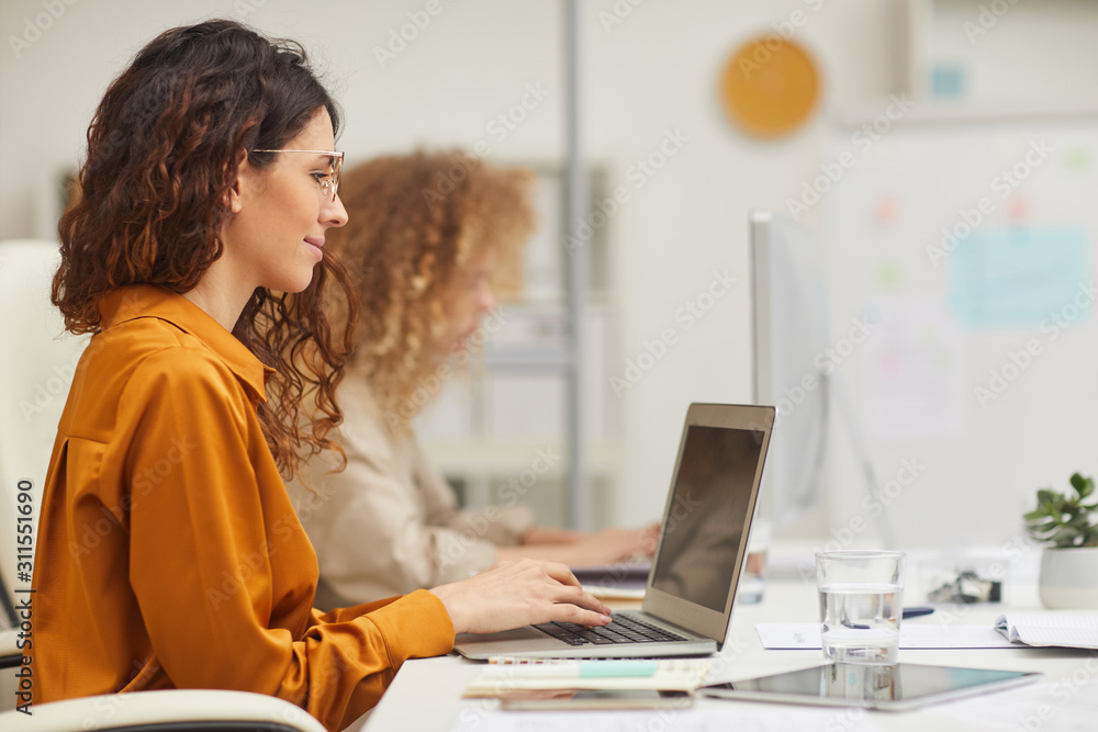 Horizontal side view shot of two Caucasian women working on computers in modern office Horizontal side view shot of two Caucasian women working on computers in modern office