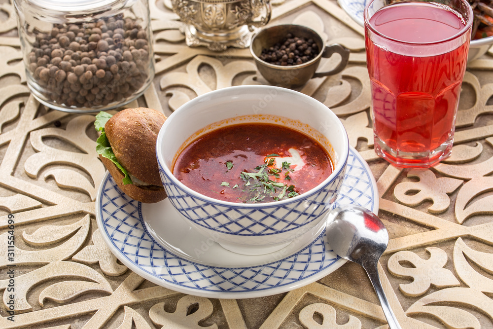 Red beetroot soup borshch with bread bun and sour cream on oriental wooden table Red beetroot soup borshch with bread bun and sour cream on oriental wooden table