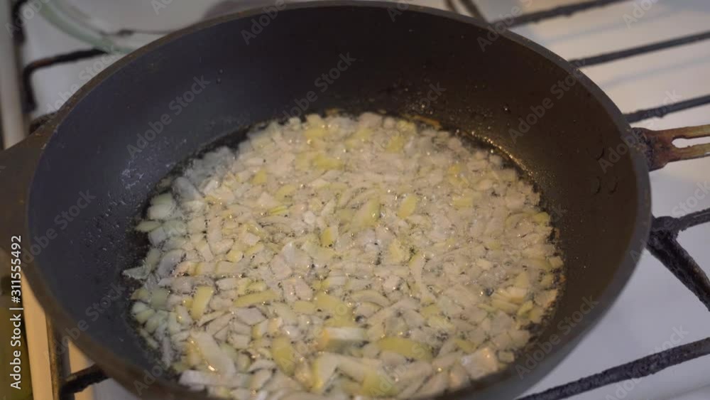 Close up minced onion being saute or quick fry in hot oil in small pan using gas stove. Onion starts to brown on the sides and getting glossy texture. Saute the onion in oil Close up minced onion being saute or quick fry in hot oil in small pan using gas stove. Onion starts to brown on the sides and getting glossy texture. Saute the onion in oil