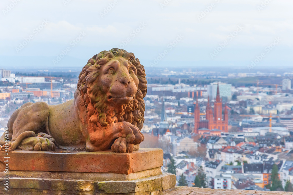 Wiesbaden in Hessen Germany view from Neroberg, in the foreground a statue of a lion, in the background a view of the city. - obrazy, fototapety, plakaty 