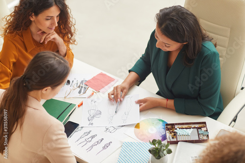 Group of young women working on fashionable clothes design together horizontal high angle shot