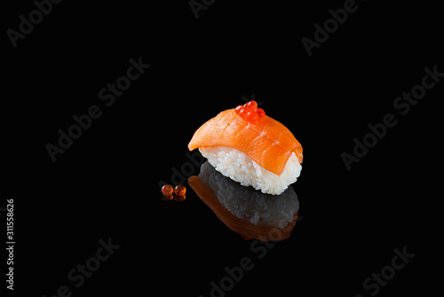 sushi nigiri with salmon - Syake with red caviar on a black background with reflection. A dish of rice and red fish