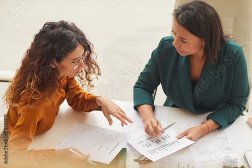 Принти на полотні Two young businesswomen working on new business plan sitting together at office