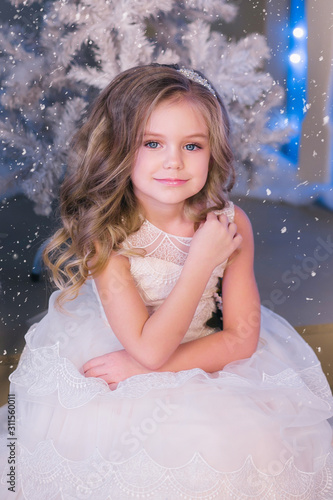 Nice girl in a white dress in Christmas decorations