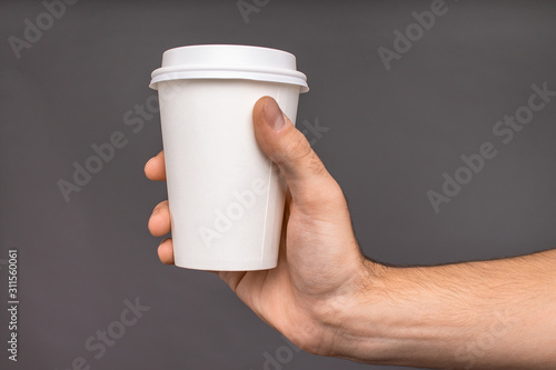 Obraz na plátně Mockup of a Cup of coffee in his hand on a dark background