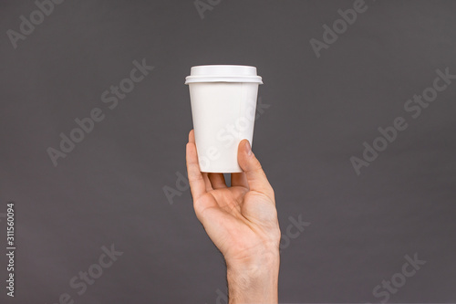 Obraz na plátně Mockup of a Cup of coffee in his hand on a dark background