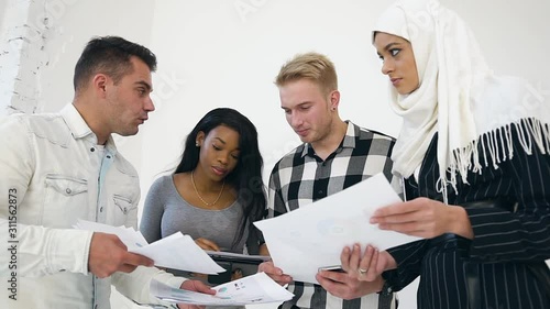 Experienced attantive 30s office workers discussing the datas from reports during their joint teamwork under business project on the white background photo