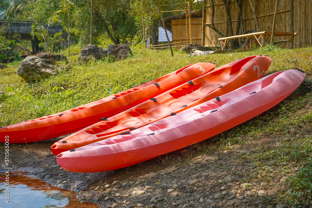 Red kayaks in the grass on the lake.