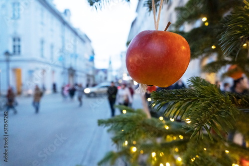 Christmas tree decoration with apples and luminous garland, handmade. the cobbled streets of Krakow are ready for Christmas and new year. people are blurred in the background photo