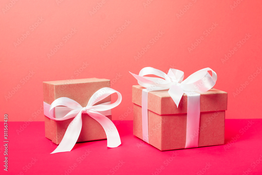Obraz premium Trendy attractive minimalistic gifts on the neon pink and coral background. Merry Christmas, St. Valentine's Day, Happy Birthday and other holidays concept.