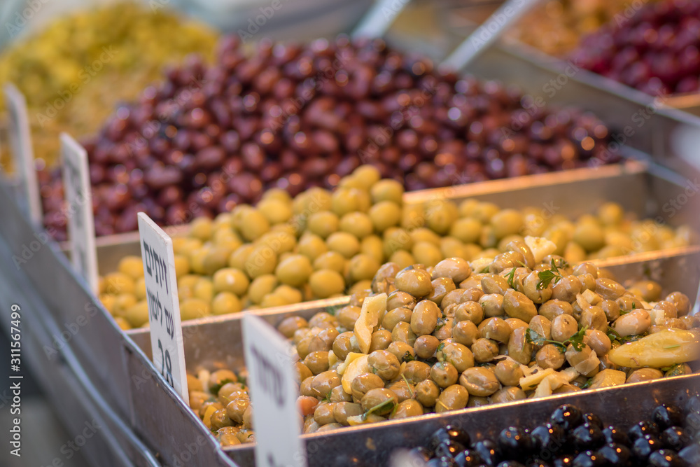Green and brown and red and black olives in metal bowls on a blurred white background, made of Syrian-Arab style. In the market in Jerusalem.