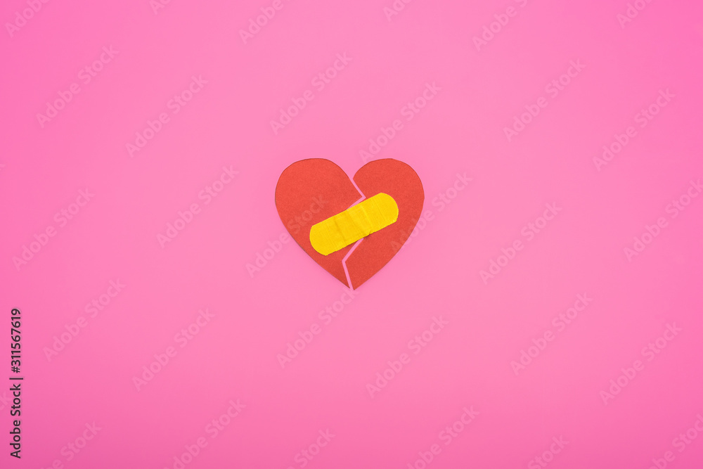 top view of broken paper heart joined with patch isolated on pink background
