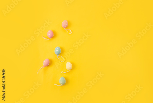 Easter holiday background. Pastel coloured decorated easter eggs on a bright yellow background