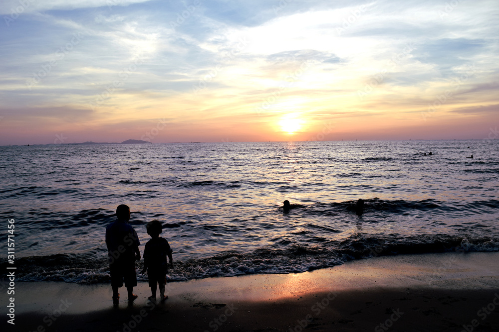 The image of the two boys standing calmly at the atmosphere of the sea and the evening sky.