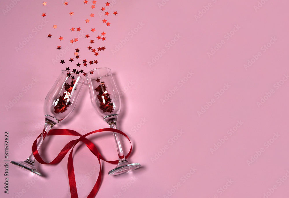 The Concept Of Valentine's Day. Two narrow empty wine glasses tied with a red ribbon, and stars on a pink background. Free space for your text. The Concept Of Valentine's Day. Two narrow empty wine glasses tied with a red ribbon, and stars on a pink background. Free space for your text.