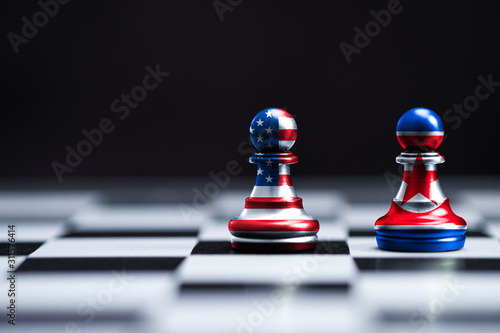 USA and North Korea flag printed screen on chess with background which both countries have conflict about nuclear weapons and sanctions crisis.