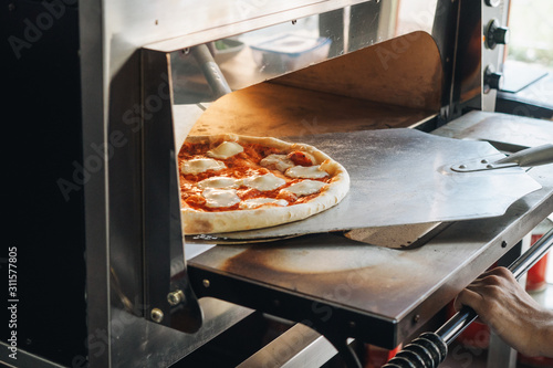 Cooking in modern pizza oven in cafe kitchen photo