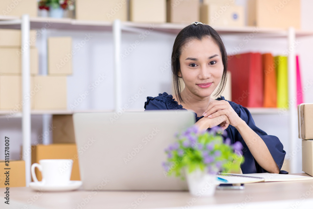 Asian women who are SME online shopping operators siting and looking at the camera. Online shopping SME entrepreneur or freelance working concept. Asian women who are SME online shopping operators siting and looking at the camera. Online shopping SME entrepreneur or freelance working concept.