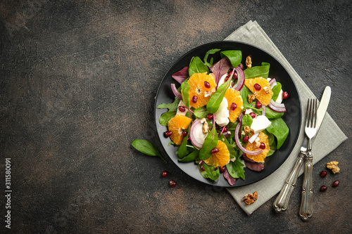 Detox salad with tangerines, mozzarella, herbs, pomegranate seeds and nuts on a dark background. Free copy space. Top view.