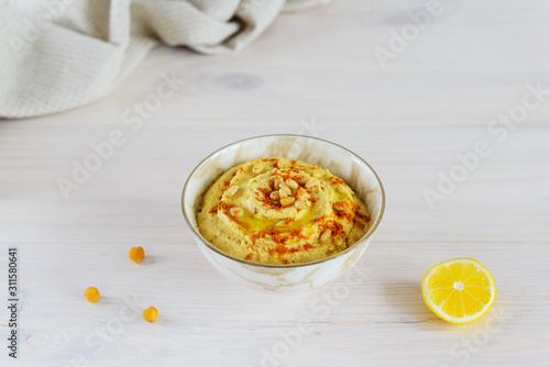 Hummus from chickpeas, tahini, garlic, paprika, oil and lemon juice in a bowl.