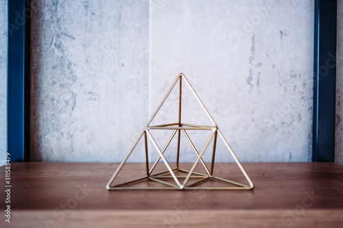 Wire shape metal pyramid on the office shelves. Interior decoration