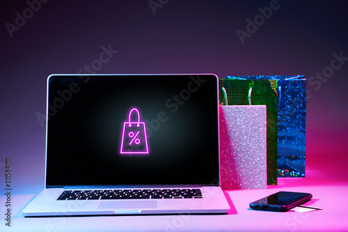 Laptop, gift packet, phone and pay card on the table in modern neon colors. photo