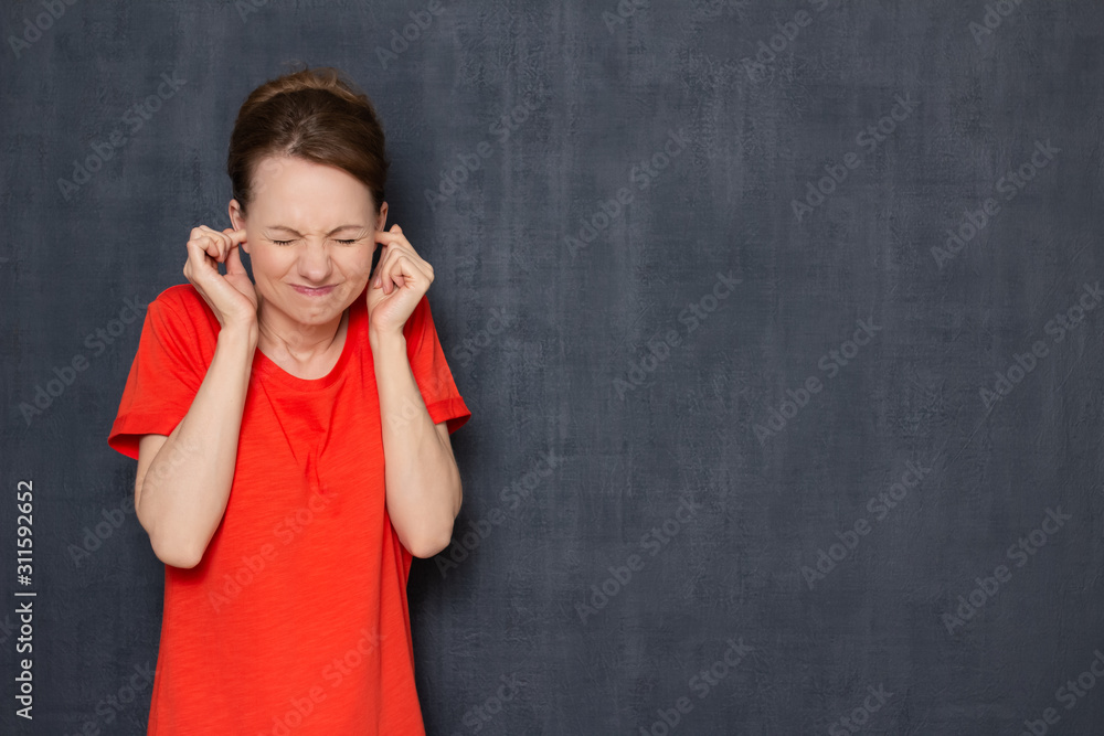 Portrait of annoyed girl with eyes closed plugging her ears Portrait of annoyed girl with eyes closed plugging her ears