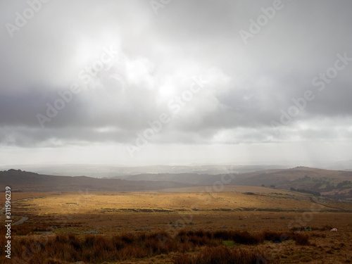 Wide angle view of glowing stratocumulus clouds lighting a part of the grassy moors of Dartmoor. Devon, United Kingdom. Travel and nature.