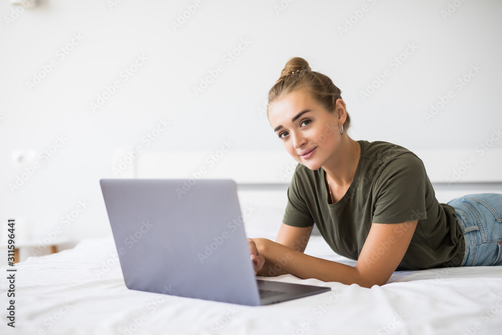 Portrait of a relaxed young woman using laptop in bed at home Portrait of a relaxed young woman using laptop in bed at home