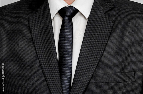 man in tie and suit close-up. the texture of a business black jacket. business style in clothes background