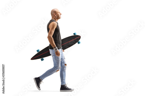 Guy carrying a longboard and walking