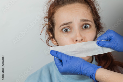 A Caucasian woman with sticky tape gluing her mouth. Hands in gloves hold a vow. The victim of violence is scared and cannot scream. Fear in eyes. The place for an inscription