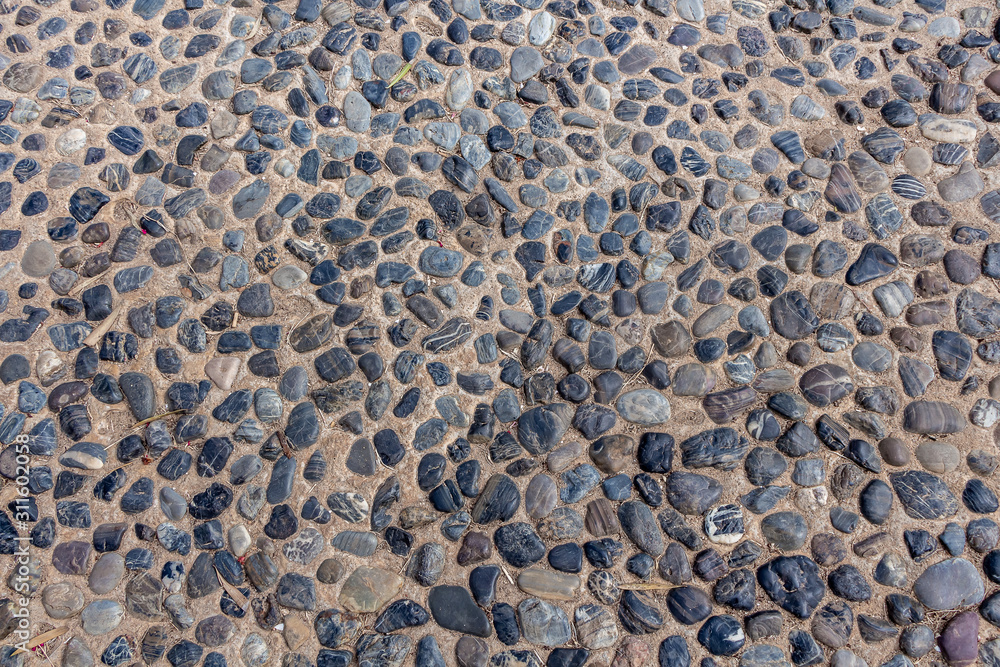 Beautiful texture of path of gray smooth stones on the orange background is in the park Beautiful texture of path of gray smooth stones on the orange background is in the park
