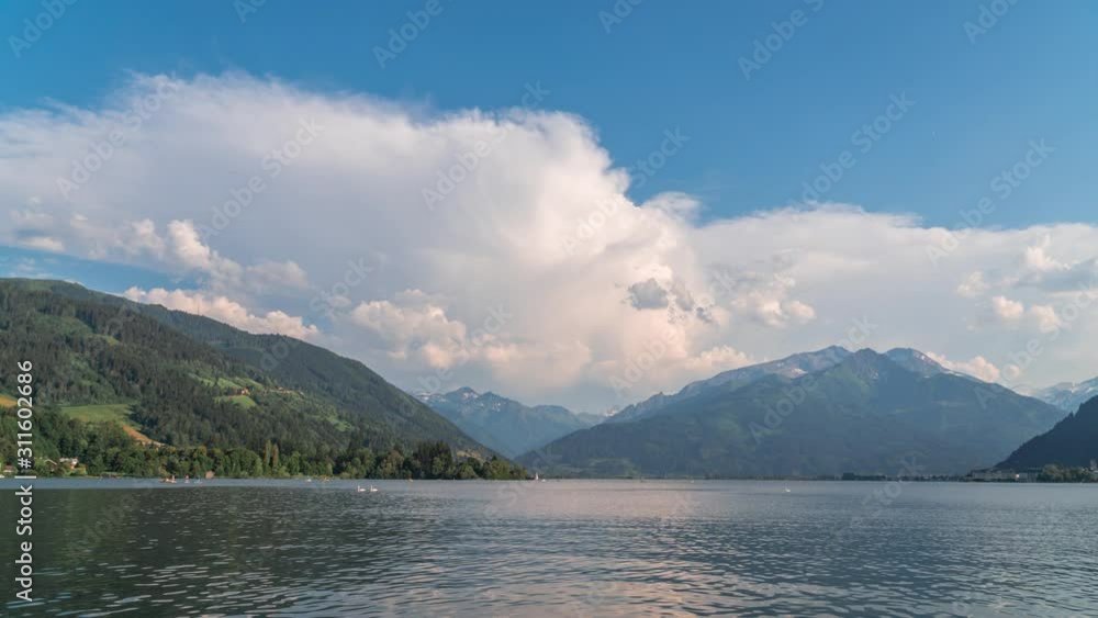 Beautiful time lapse summer scene with lake in the Dolomites mountains. People swim, go on catamarans, boats and SOP boards, Zell am See, Salzburger, Austria, travel tourism concept design Beautiful time lapse summer scene with lake in the Dolomites mountains. People swim, go on catamarans, boats and SOP boards, Zell am See, Salzburger, Austria, travel tourism concept design