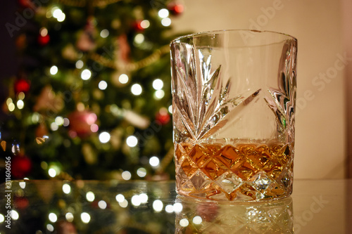 A festive glass of Whiskey with Christmas tree in background photo