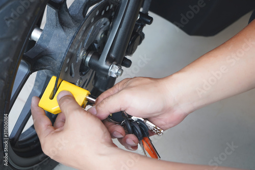Fotografie Motorcycle owner use a disc brake lock on a motorbike
