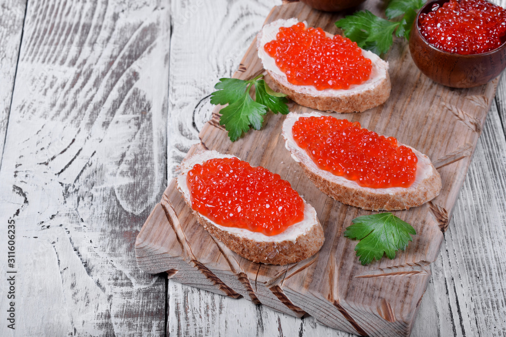 Sandwiches with bran bread, red caviar and butter on white wooden table Sandwiches with bran bread, red caviar and butter on white wooden table